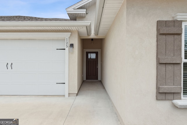 125 The Villas Way, Kingsland, GA 31548 - view of exterior entry with stucco siding, an attached garage, and a shingled roof