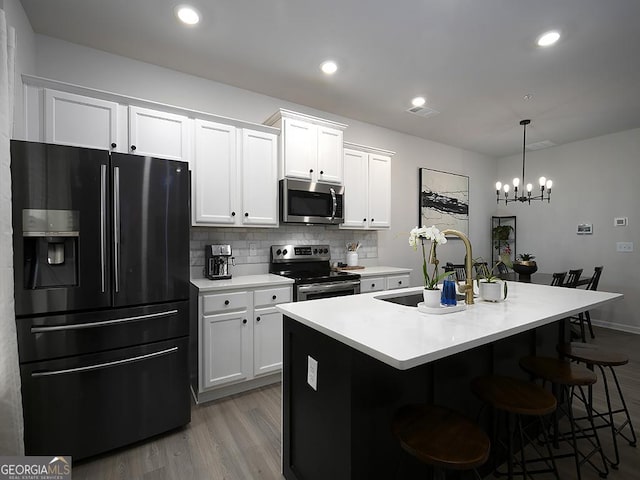 2108 Remy Ct, Kennesaw, GA 30144 - kitchen with stainless steel appliances, a sink, wood finished floors, backsplash, and white cabinetry