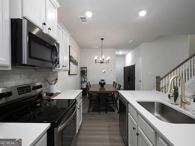 2108 Remy Ct, Kennesaw, GA 30144 - kitchen featuring appliances with stainless steel finishes, a sink, wood finished floors, a chandelier, and decorative backsplash