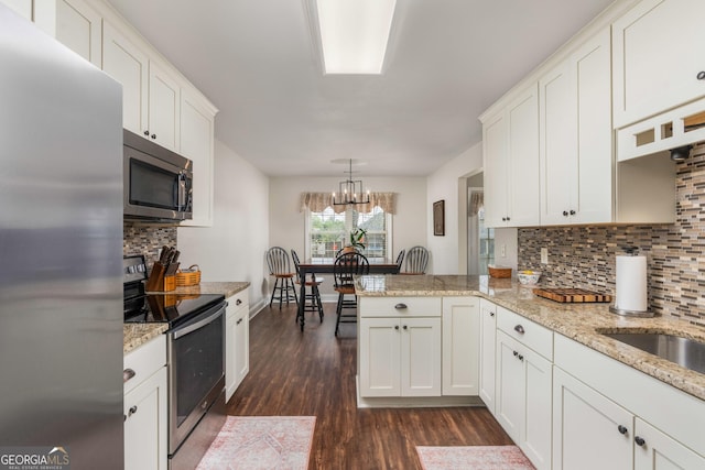 900 Bay Laurel Cir, Warner Robins, GA 31088 - kitchen with appliances with stainless steel finishes, dark wood-style flooring, backsplash, a peninsula, and white cabinetry