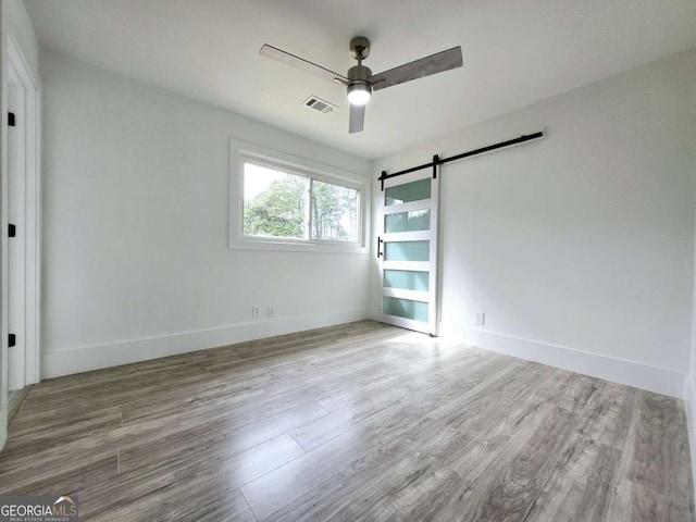 2400 Glenrock Dr, Decatur, GA 30032 - unfurnished bedroom featuring wood finished floors, a barn door, baseboards, and a ceiling fan
