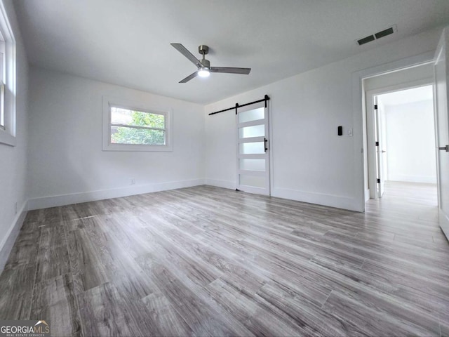 2400 Glenrock Dr, Decatur, GA 30032 - unfurnished bedroom featuring a barn door, wood finished floors, baseboards, and ceiling fan