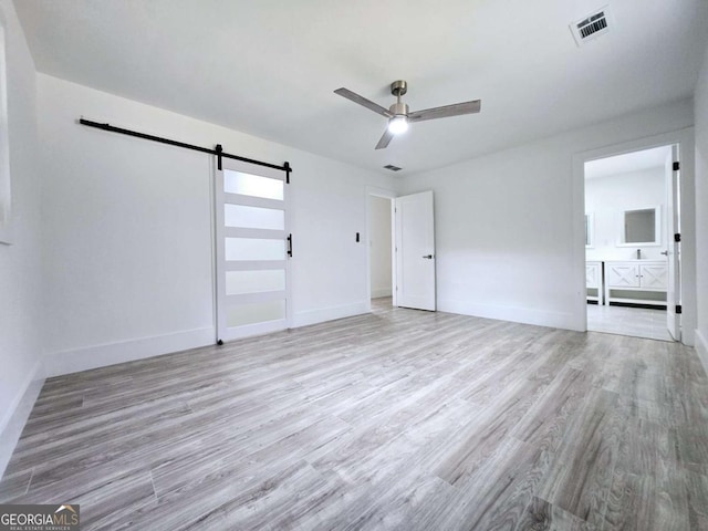 2400 Glenrock Dr, Decatur, GA 30032 - unfurnished bedroom with a barn door, light wood-type flooring, baseboards, and ceiling fan