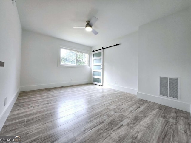 2400 Glenrock Dr, Decatur, GA 30032 - unfurnished room with a barn door, wood finished floors, ceiling fan, and baseboards