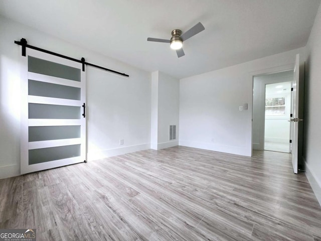 2400 Glenrock Dr, Decatur, GA 30032 - unfurnished room featuring a barn door, ceiling fan, wood finished floors, and baseboards
