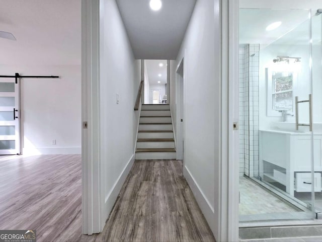2400 Glenrock Dr, Decatur, GA 30032 - hallway featuring a barn door, wood finished floors, stairway, and baseboards
