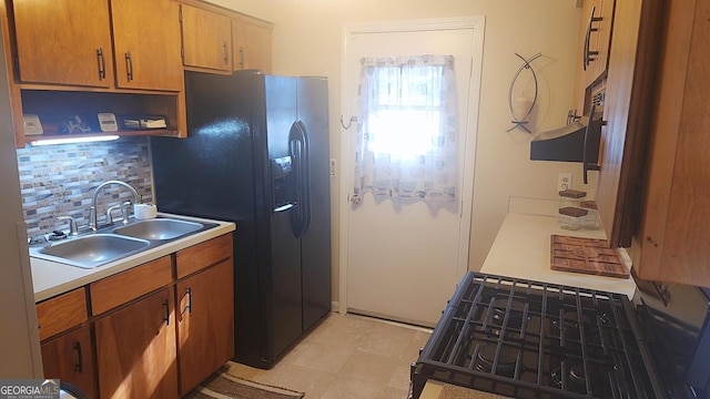 5802 Blueridge Dr, Columbus, GA 31907 - kitchen featuring a sink, tasteful backsplash, black fridge, light countertops, and brown cabinetry