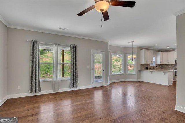 47 Whitley Ct, Dallas, GA 30157 - unfurnished living room featuring dark wood-style floors, baseboards, crown molding, ceiling fan, and a sink