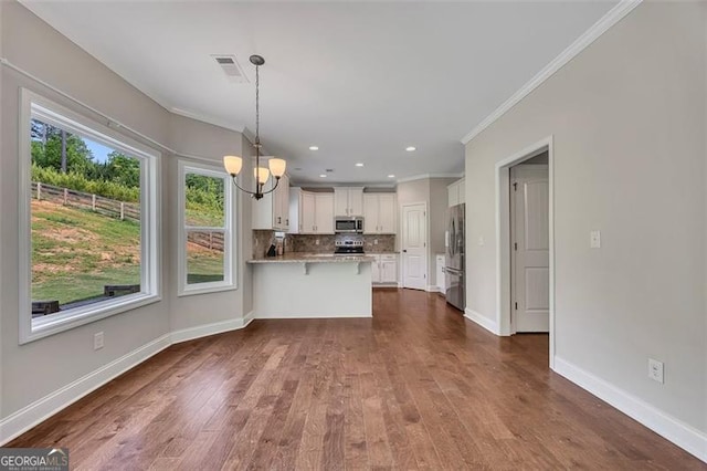 47 Whitley Ct, Dallas, GA 30157 - kitchen with stainless steel appliances, a chandelier, a peninsula, crown molding, and white cabinetry