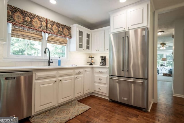 kitchen with stainless steel appliances, a sink, tasteful backsplash, dark wood-style floors, and light countertops