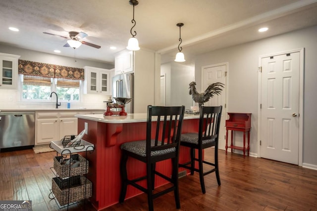 kitchen with appliances with stainless steel finishes, white cabinetry, light countertops, ceiling fan, and dark wood-style floors