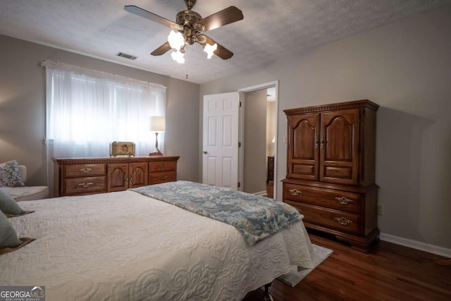 bedroom with dark wood-style flooring, baseboards, a ceiling fan, and a textured ceiling