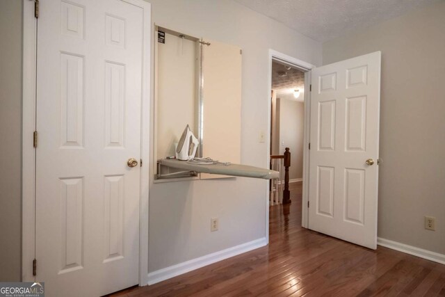 unfurnished bedroom featuring wood finished floors, baseboards, and a textured ceiling