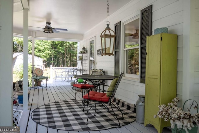 wooden deck with outdoor dining area and ceiling fan