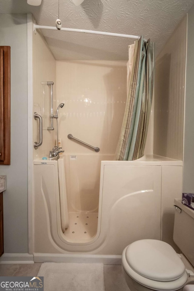 bathroom featuring a shower with shower curtain, toilet, and tile patterned floors