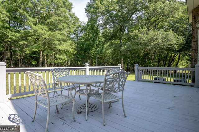 wooden deck with outdoor dining space and view of wooded area