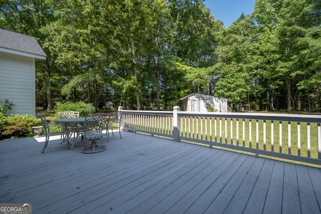 wooden deck with outdoor dining area, a lawn, and view of scattered trees