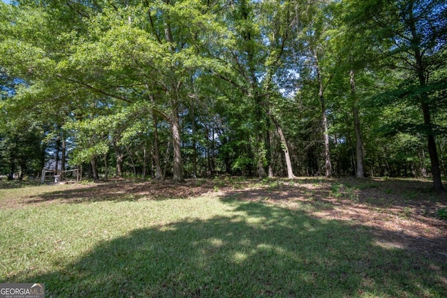 view of green lawn with a forest view