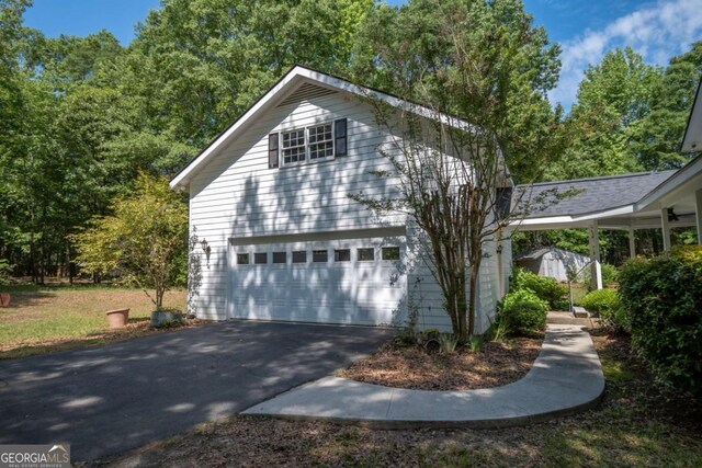 view of home's exterior with a garage, an outbuilding, and asphalt driveway