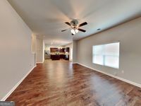 620 Sedona Loop, Hampton, GA 30228 - unfurnished living room with baseboards, a ceiling fan, and wood finished floors