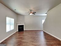 620 Sedona Loop, Hampton, GA 30228 - unfurnished living room featuring a fireplace, baseboards, ceiling fan, and wood finished floors