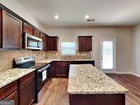 620 Sedona Loop, Hampton, GA 30228 - kitchen featuring appliances with stainless steel finishes, a kitchen island, light wood-style flooring, decorative backsplash, and recessed lighting