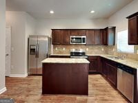 620 Sedona Loop, Hampton, GA 30228 - kitchen featuring stainless steel appliances, a kitchen island, tasteful backsplash, light countertops, and dark brown cabinetry