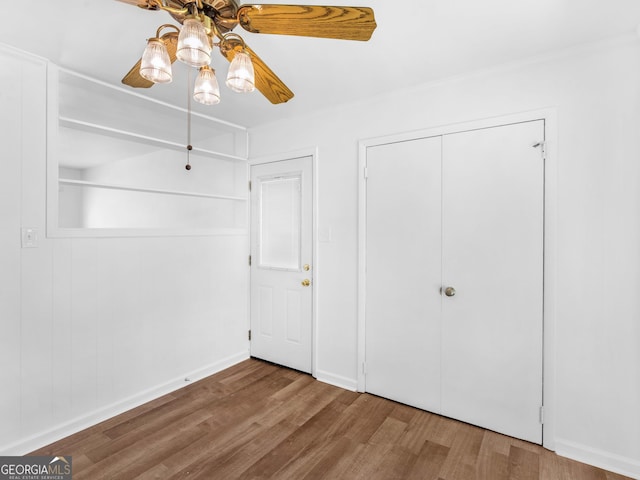 unfurnished bedroom with wood finished floors, a closet, ceiling fan, and baseboards
