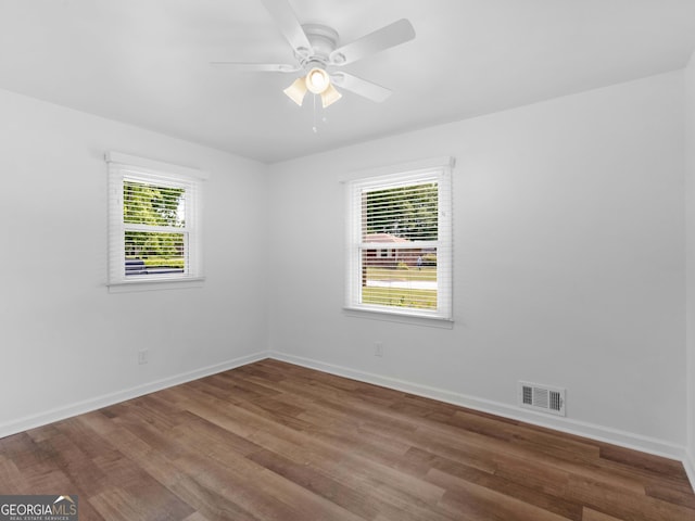 unfurnished room with wood finished floors, a ceiling fan, and baseboards