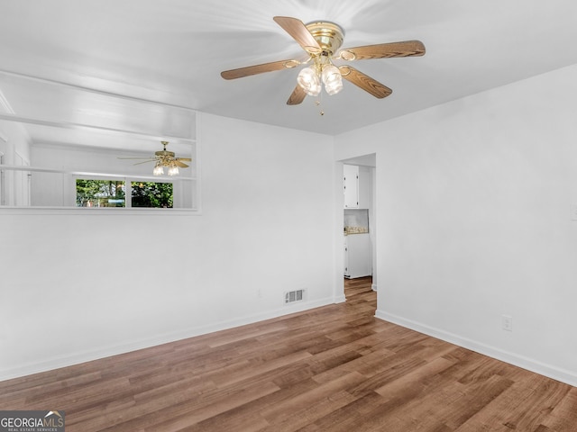 empty room with ceiling fan, wood finished floors, and baseboards