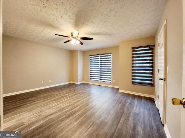 spare room featuring dark wood-style flooring, ceiling fan, a textured ceiling, and baseboards