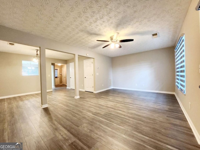 unfurnished living room with dark wood-style flooring, a ceiling fan, baseboards, and a textured ceiling