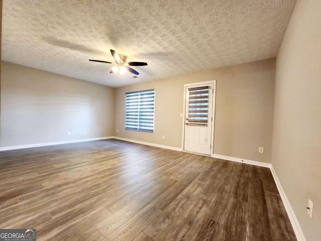 unfurnished room with dark wood-style flooring, ceiling fan, and baseboards