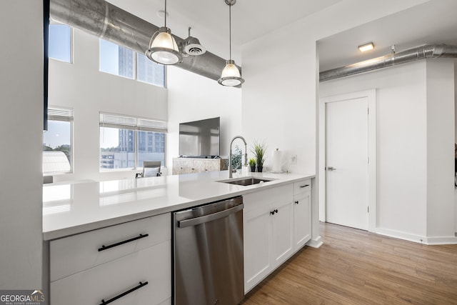 260N 18th St Unit 10326, Atlanta, GA 30363 - kitchen with stainless steel dishwasher, white cabinetry, light countertops, pendant lighting, and light wood finished floors