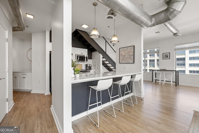 260N 18th St Unit 10326, Atlanta, GA 30363 - kitchen with stainless steel microwave, light wood-style flooring, a breakfast bar, decorative light fixtures, and light countertops