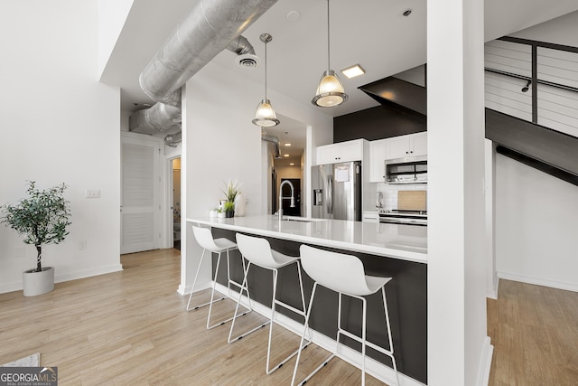 260N 18th St Unit 10326, Atlanta, GA 30363 - kitchen with appliances with stainless steel finishes, a breakfast bar area, white cabinets, and light wood-style floors