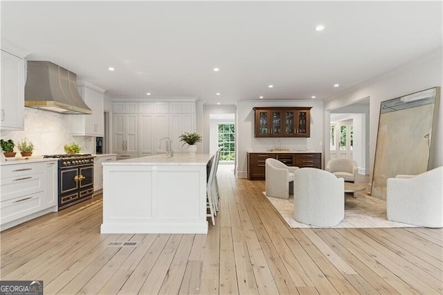 3625 Tuxedo Rd NW, Atlanta, GA 30305 - kitchen featuring wall chimney exhaust hood, double oven range, light countertops, white cabinetry, and crown molding