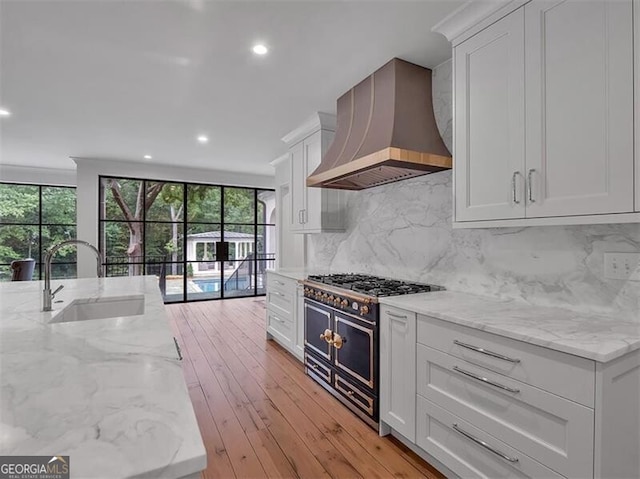 3625 Tuxedo Rd NW, Atlanta, GA 30305 - kitchen with custom exhaust hood, a sink, range with two ovens, white cabinets, and light stone countertops