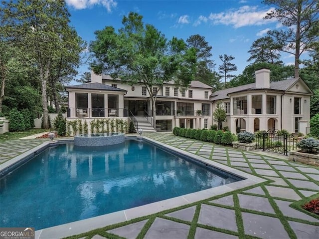 3625 Tuxedo Rd NW, Atlanta, GA 30305 - back of property with a sunroom, stairway, a chimney, a patio area, and a pool with connected hot tub
