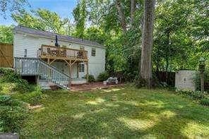 back of property featuring a wooden deck, stairway, and a lawn