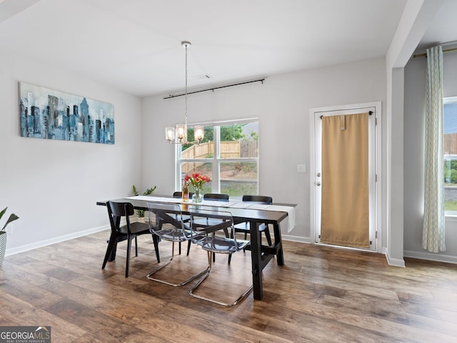 dining space featuring wood finished floors, a chandelier, and baseboards