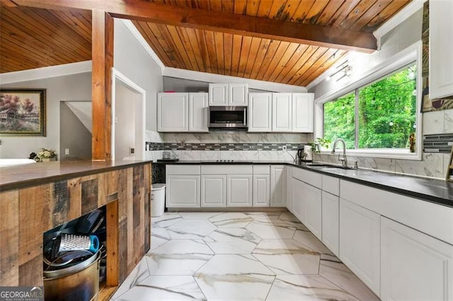4882 Rock Haven Dr SW, Lilburn, GA 30047 - kitchen with stainless steel microwave, wooden ceiling, light marble finish floors, backsplash, and dark countertops