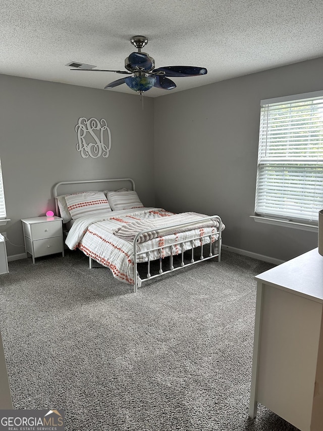 carpeted bedroom with a textured ceiling, baseboards, and a ceiling fan