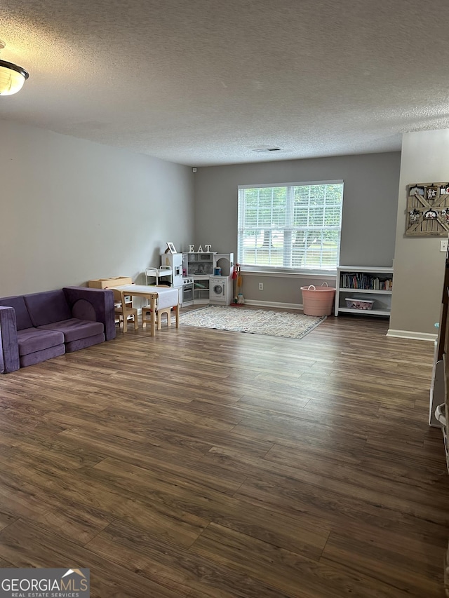 living room featuring dark wood-type flooring, a textured ceiling, and baseboards
