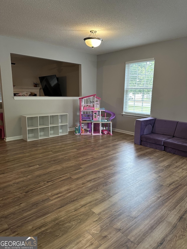 rec room featuring wood finished floors, baseboards, and a textured ceiling