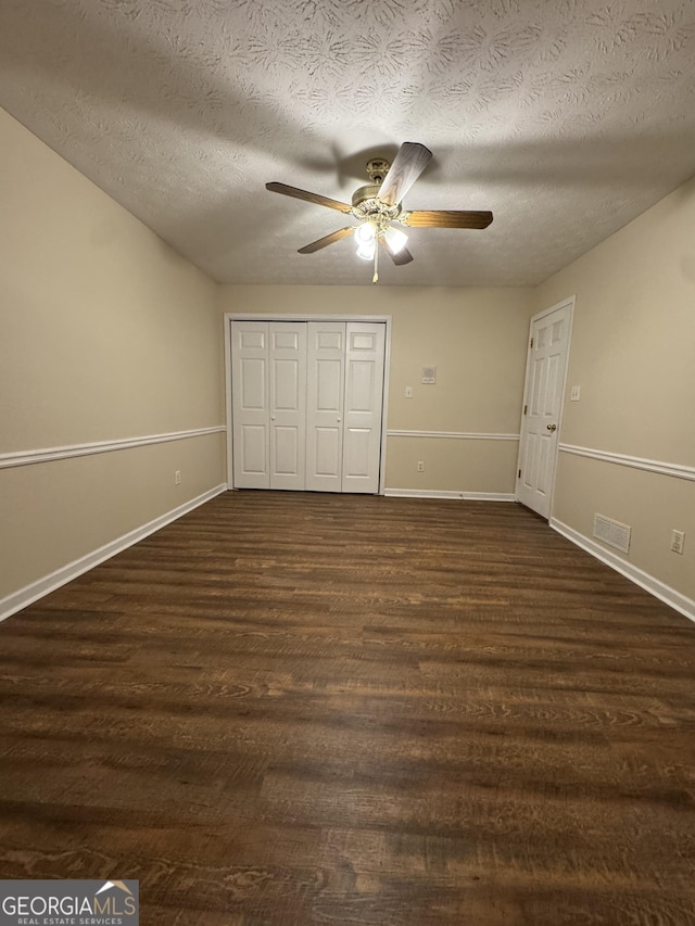 143 Tracy Ln, Mcdonough, GA 30253 - unfurnished bedroom with dark wood-style floors, a textured ceiling, baseboards, a closet, and a ceiling fan
