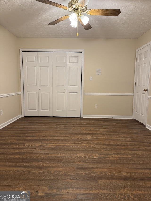 143 Tracy Ln, Mcdonough, GA 30253 - unfurnished bedroom with a textured ceiling, dark wood-style floors, a closet, baseboards, and a ceiling fan