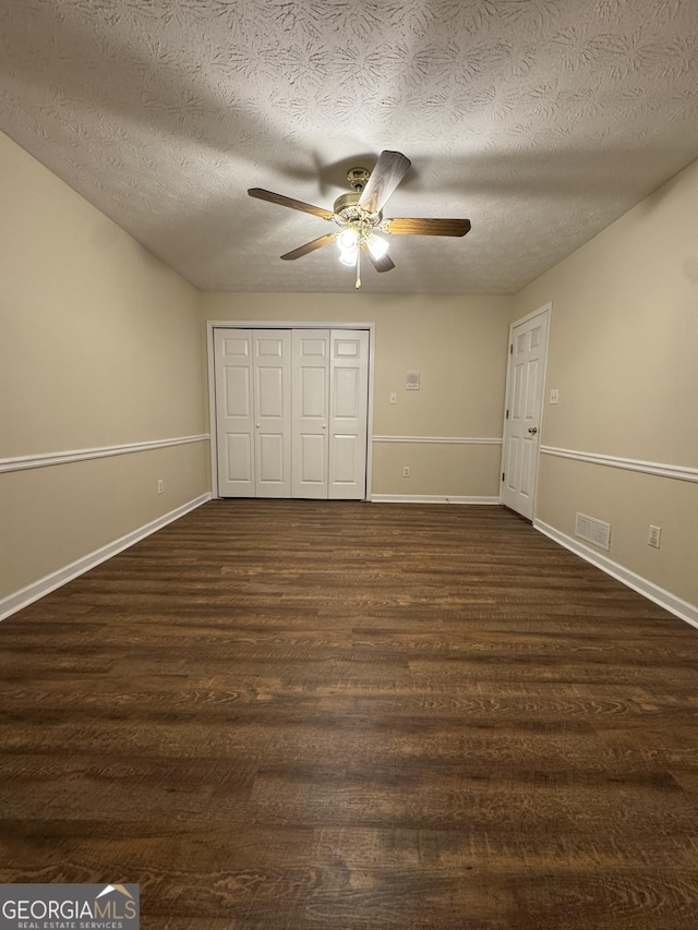 143 Tracy Ln, Mcdonough, GA 30253 - unfurnished bedroom with dark wood-type flooring, a textured ceiling, a closet, baseboards, and ceiling fan