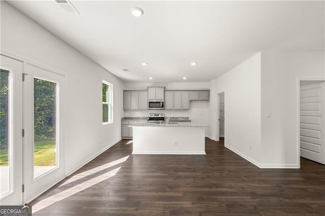 45 Vermillion Way, Covington, GA 30016 - kitchen featuring appliances with stainless steel finishes, gray cabinetry, recessed lighting, dark wood finished floors, and an island with sink