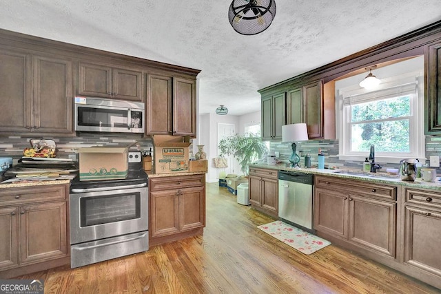 1315 Arden Dr SW, Marietta, GA 30008 - kitchen featuring appliances with stainless steel finishes, a sink, light wood-style floors, tasteful backsplash, and a textured ceiling